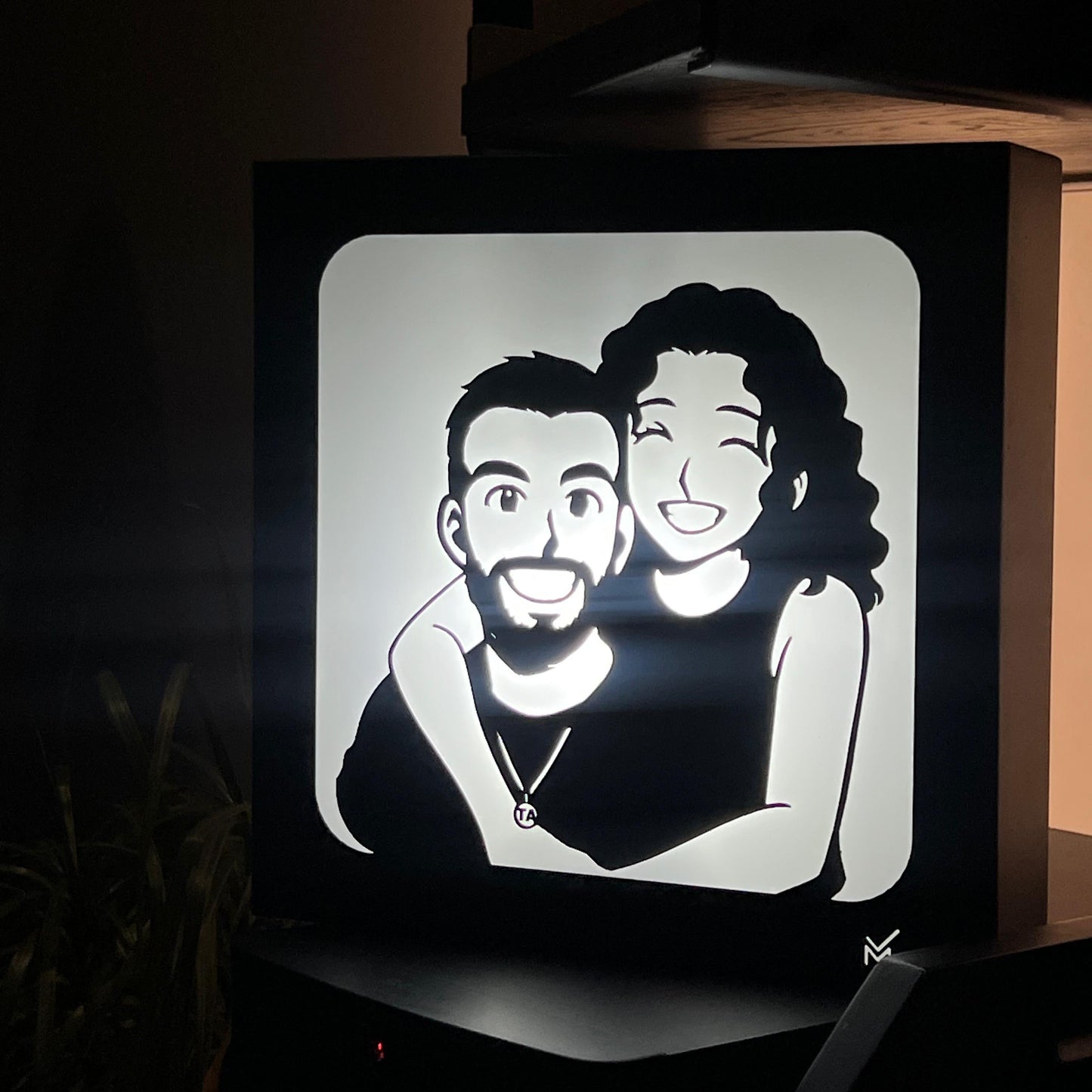Light box with a black and white illustration of two people on a dark background